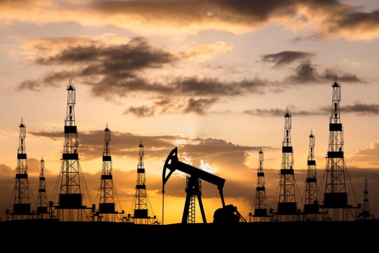 Oil field with rigs and pumps at sunset